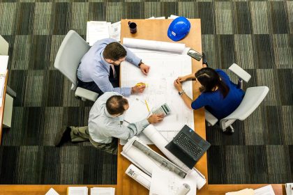 Equipe reunida analisando plantas e documentos de um projeto de construção sobre uma mesa