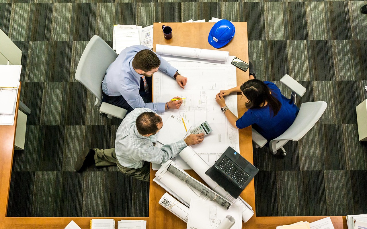 Equipe reunida analisando plantas e documentos de um projeto de construção sobre uma mesa